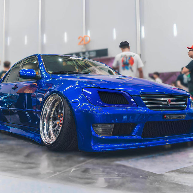 "A modified Altezza with aftermarket wheels, a lowered stance, and a custom front lip, enhancing its sporty and aggressive appeal."