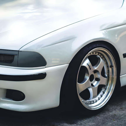 Front three-quarter view of a BMW E39 Alpina B10, featuring unique Alpina styling cues such as the distinctive front spoiler and multi-spoke wheels, highlighting the exclusive performance enhancements.

