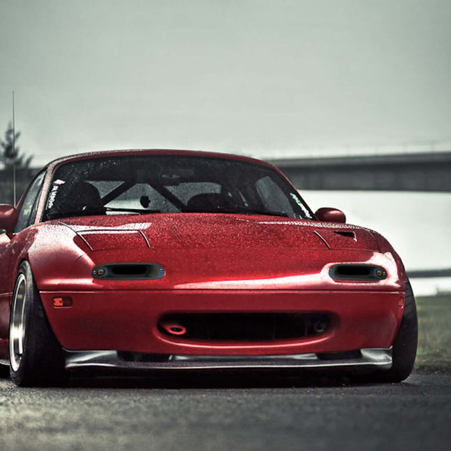 Miata MX-5 NA Roadster front splitter, carbon fiber aerodynamic upgrade, wind tunnel-tested airflow, increased downforce, improved high-speed stability, race-spec track handling upgrade.

