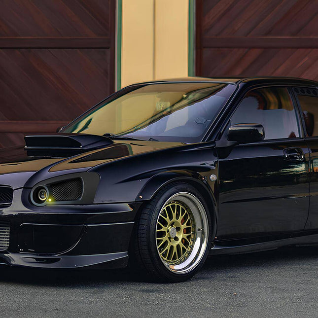 Side profile of a 2004 Subaru Impreza WRX STi in Java Black Pearl, equipped with gold BBS wheels and Brembo brakes, capturing the iconic color combination associated with Subaru's rally heritage.

