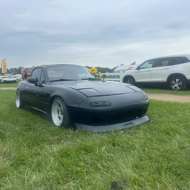 Miata MX-5 NA Roadster full body kit, JDM-style front bumper, carbon fiber side skirts, rear diffuser, vented fenders, front lip, aggressive aerodynamics, lightweight race panels, track-inspired styling.

