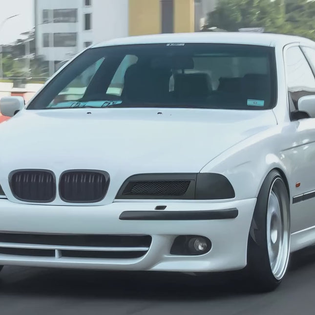 A BMW E39 5 Series displayed at a classic car show, with spectators admiring its design and engineering, underscoring its status as a modern classic in the automotive world.

